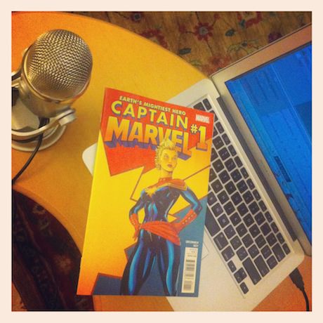 Still life photograph of a microphone, Captain Marvel comic, and a MacBook.